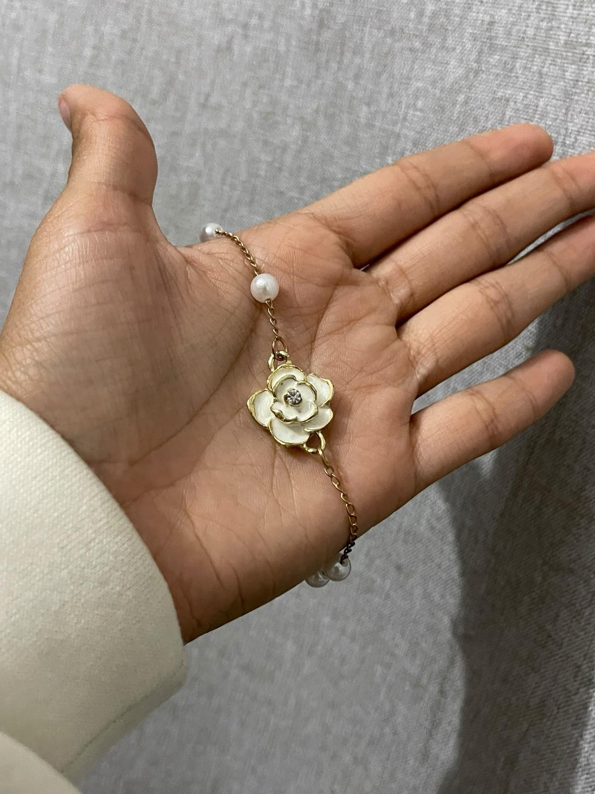 Pulsera dorada con dijes de flor blanca y perlas, foto 1 de 1
