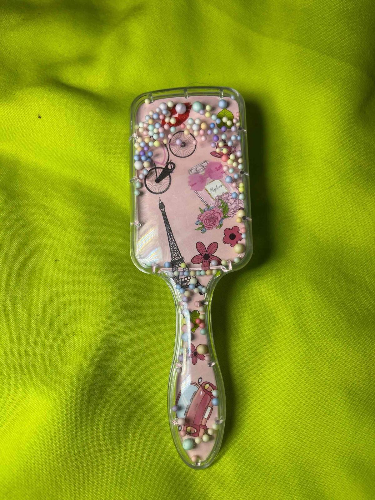 Cepillo de cabello transparente con diseño parisino y bolitas decorativas, foto 1 de 2