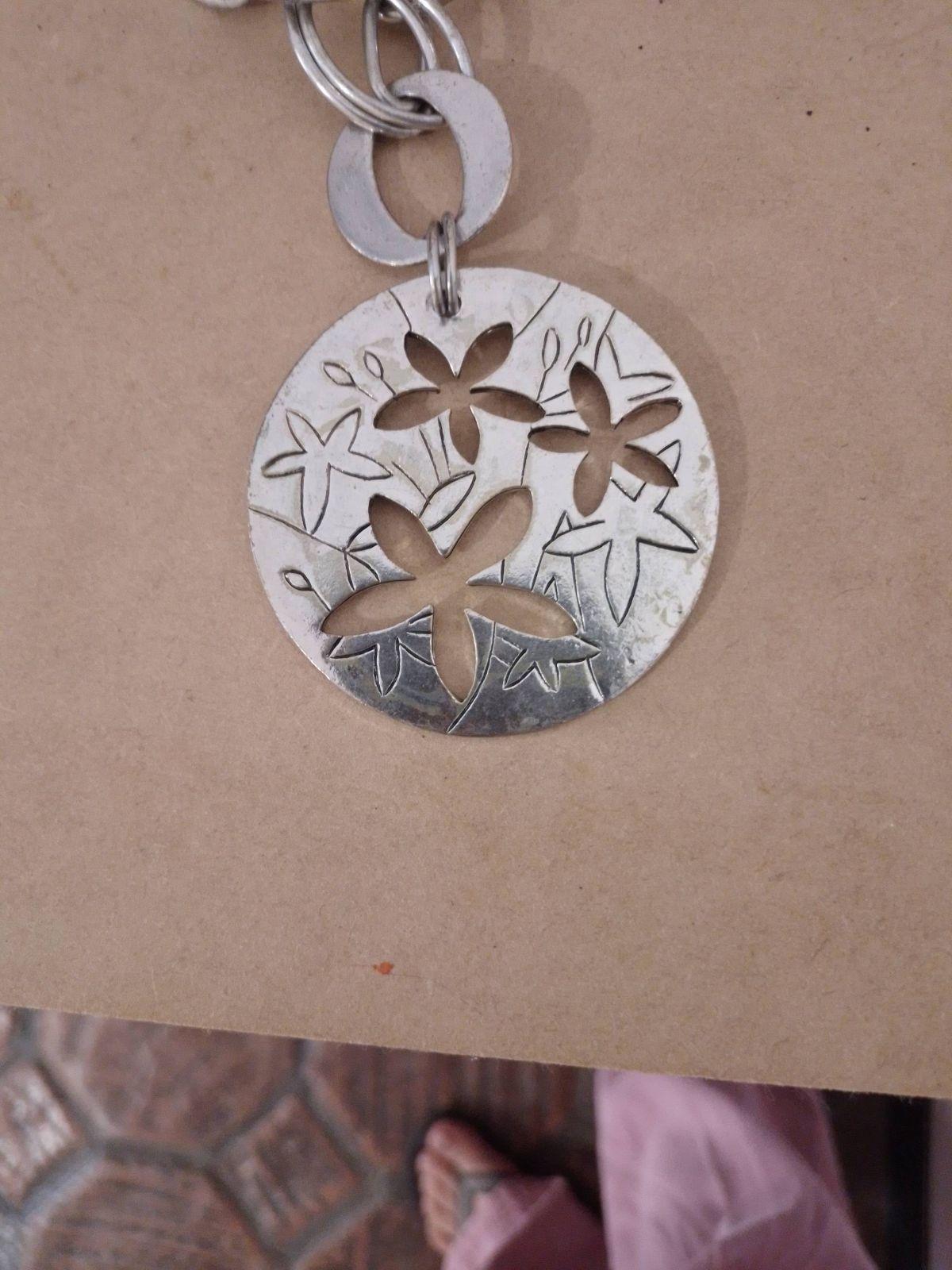 Collar de metal plateado con dije circular y flores, foto 2 de 4